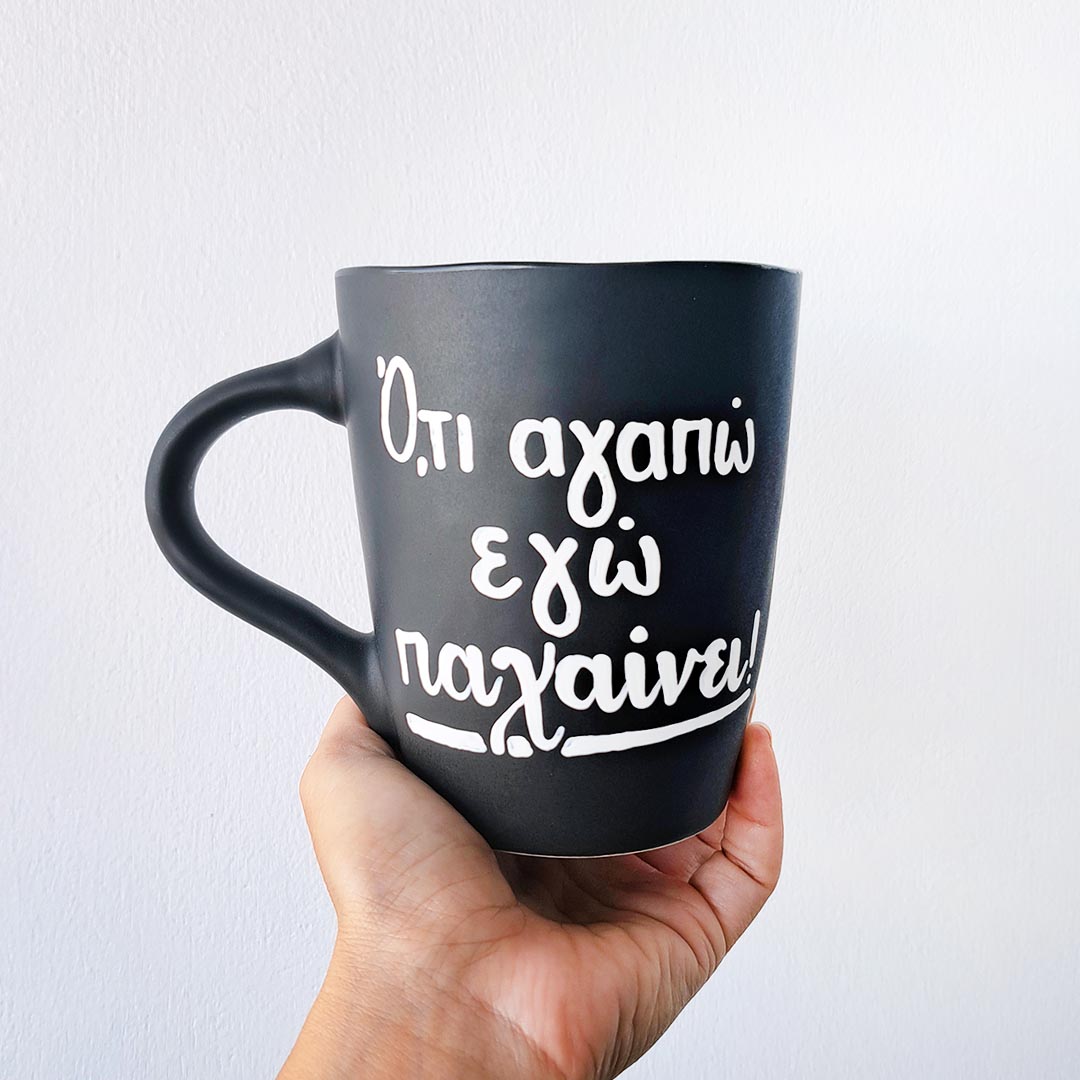 Hand painted black ceramic mug, "'Ο,τι αγαπώ εγώ παχαίνει"