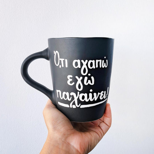 Hand painted black ceramic mug, "'Ο,τι αγαπώ εγώ παχαίνει"