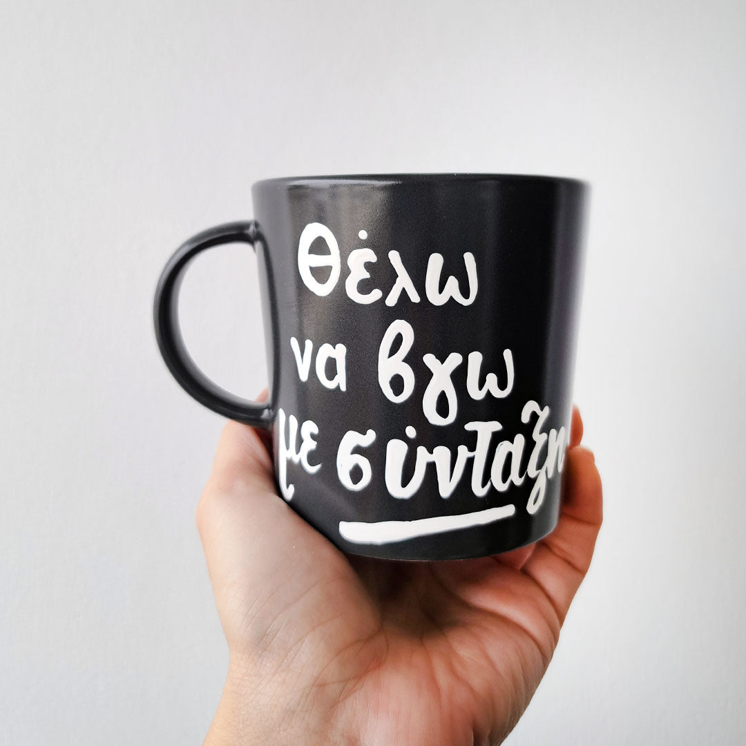 Hand painted black ceramic mug, "Θέλω να βγω με σύνταξη"